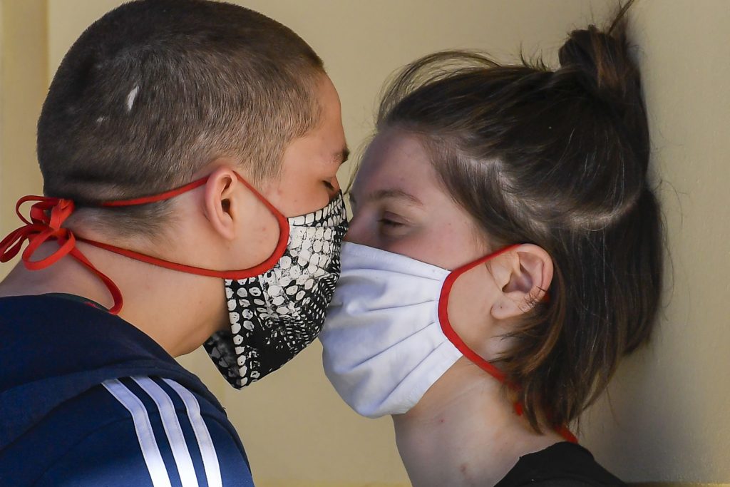 Cuplu care se sărută cu mască.